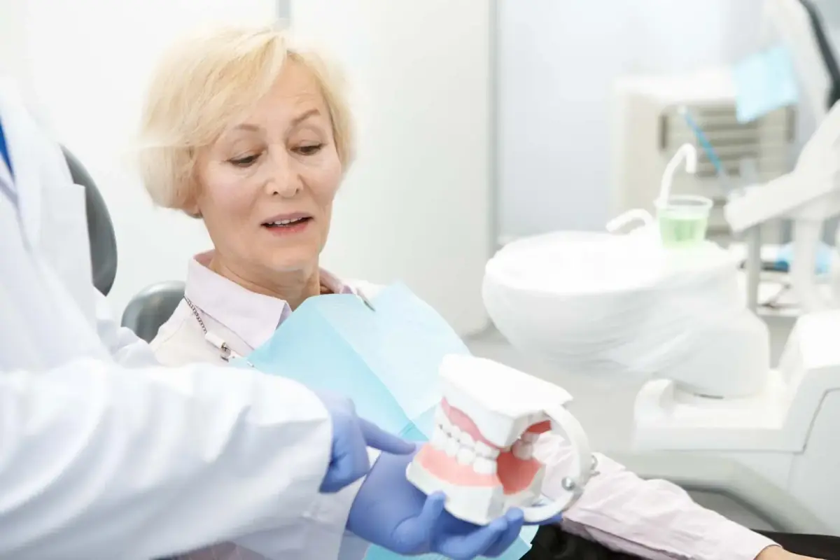 Dentist explaining implant-supported dentures with a model